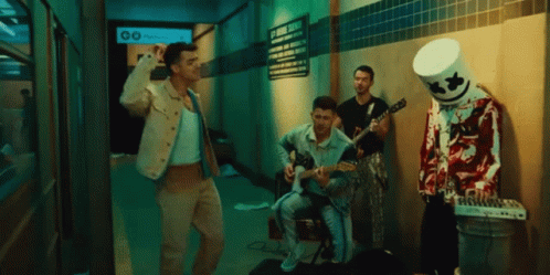 A Man In A Marshmallow Costume Plays A Guitar In A Dark Hallway GIF
