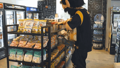 a man in a mascot costume is standing in front of a display of snacks