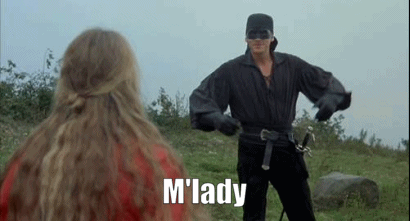 A Man In A Mask Is Holding A Sword In Front Of A Woman In A Red Dress . GIF