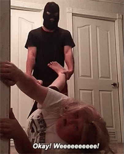 A Man In A Mask Is Holding A Woman 'S Leg In A Doorway And Says Okay ! Weeeee ! GIF