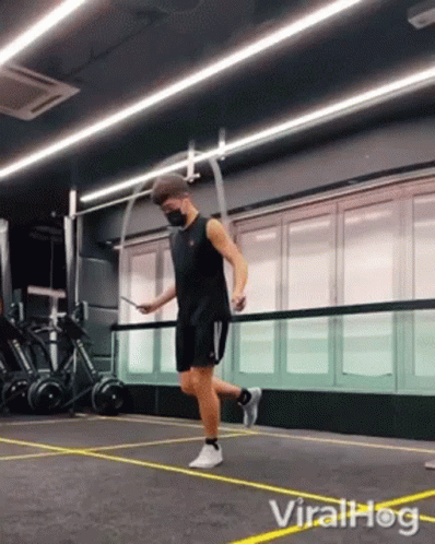 A Man In A Mask Is Jumping A Jump Rope In A Gym . GIF