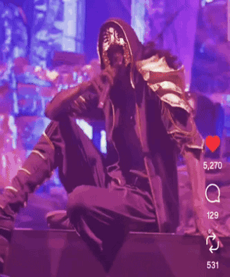 A Man In A Mask Is Singing Into A Microphone On Stage GIF
