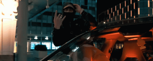 a man in a mask is sitting in a car and giving the middle finger
