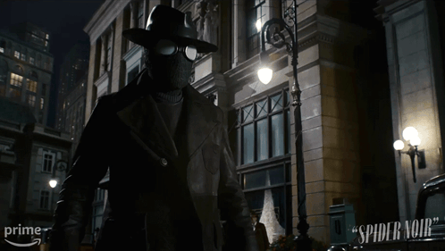 A Man In A Mask Is Standing In Front Of A Building That Says Spider-Man On It GIF