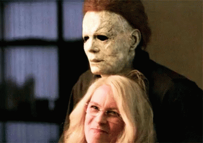 A Man In A Mask Is Standing Next To A Woman . GIF