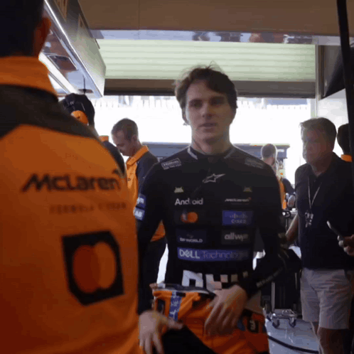 A Man In A Mclaren Jacket Is Standing In A Garage GIF