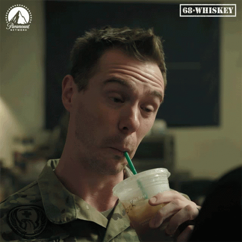 A Man In A Military Uniform Drinks Through A Straw From A Plastic Cup With Gb-Whiskey Written On The Bottom GIF