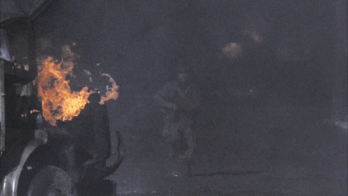 A Man In A Military Uniform Is Running In Front Of A Truck GIF