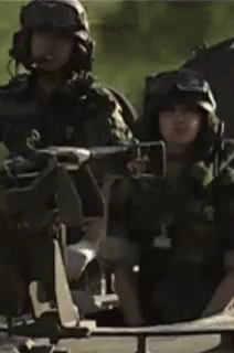 a man in a military uniform is sitting in a vehicle with other soldiers .