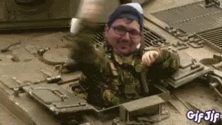 A Man In A Military Uniform Is Sitting In The Back Of A Military Vehicle . GIF