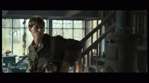 A Man In A Military Uniform Is Standing In A Dark Room GIF