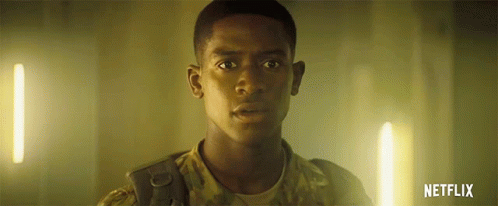 A Man In A Military Uniform Is Standing In A Dark Room With A Netflix Logo In The Corner . GIF