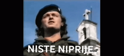 A Man In A Military Uniform Is Standing In Front Of A Church With The Words " Niste Niprive " On The Bottom Right GIF