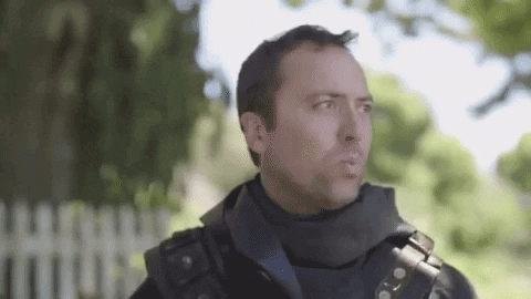 A Man In A Military Uniform Is Standing In Front Of A Fence . GIF