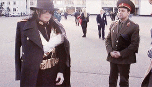 A Man In A Military Uniform Is Standing Next To Another Man GIF