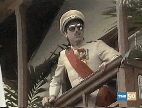 A Man In A Military Uniform Is Standing On A Balcony With A Sign That Says Tvm 50 On It GIF