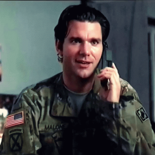 A Man In A Military Uniform Is Talking On A Cell Phone With Malon Written On His Sleeve GIF