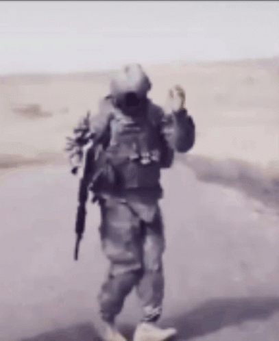 A Man In A Military Uniform Is Walking Down A Road GIF