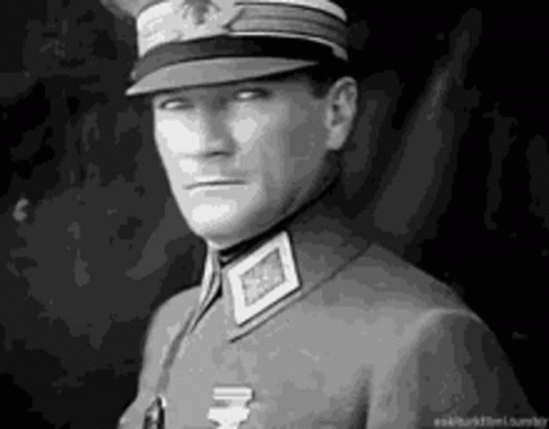 A Man In A Military Uniform Is Wearing A Hat And Looking At The Camera . GIF