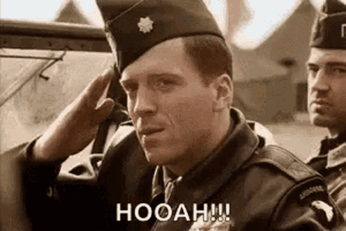 A Man In A Military Uniform Salutes While Another Man Looks On . GIF