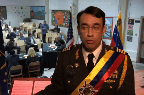 A Man In A Military Uniform Stands At A Podium In Front Of A Group Of People GIF