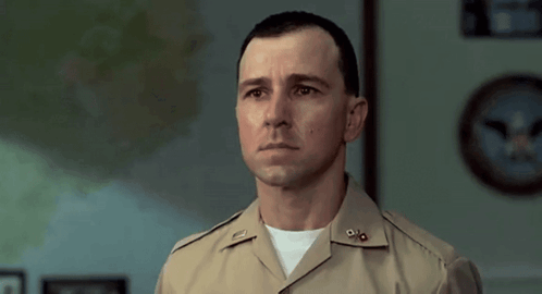 A Man In A Military Uniform Stands In Front Of A Clock GIF
