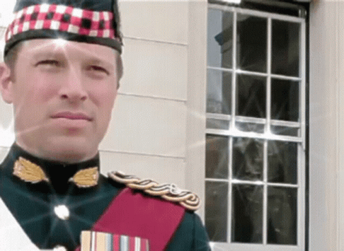 A Man In A Military Uniform Stands In Front Of A White Building GIF
