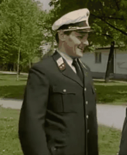 A Man In A Military Uniform With A White Hat Is Smiling . GIF