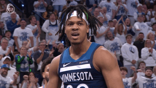 A Man In A Minnesota Jersey Stands In Front Of A Crowd Of People GIF