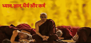 A Man In A Monk 'S Robe Sits In Front Of A Group Of People With Their Heads On The Ground GIF