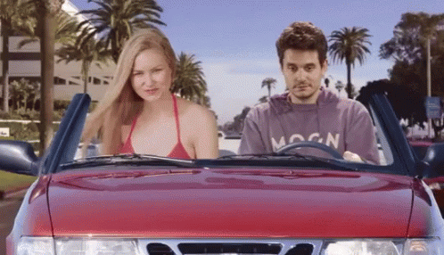 A Man In A Moon Sweatshirt Is Driving A Red Car GIF