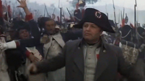 A Man In A Napoleon Hat Stands In Front Of A Crowd GIF