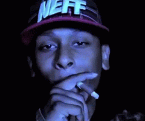 A Man In A Neff Hat Is Smoking A Cigarette . GIF