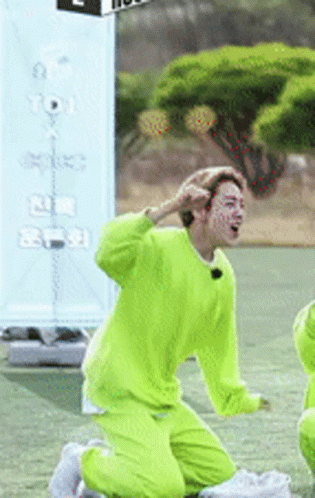 A Man In A Neon Green Outfit Is Kneeling On The Ground GIF
