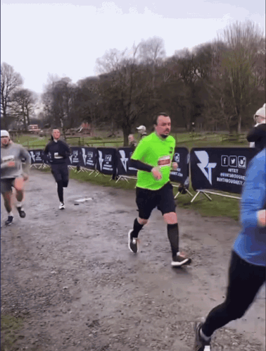 A Man In A Neon Green Shirt Is Running In Front Of A Banner That Says #Test GIF