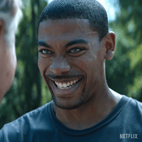 A Man In A Netflix Shirt Smiles At Another Man GIF