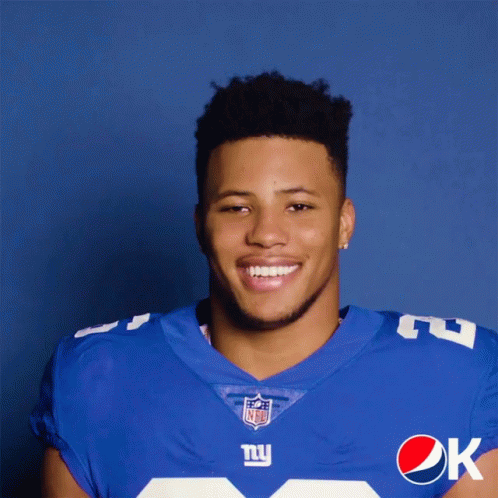a man in a new york giants uniform is holding a pepsi can