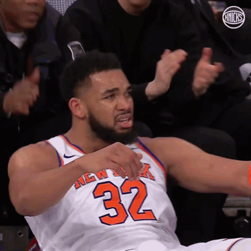 A Man In A New York Knicks Jersey Is Sitting On The Floor GIF