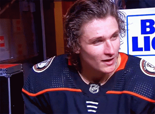 A Man In A Nhl Jersey Stands In Front Of A Sign That Says B Lic GIF