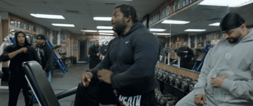A Man In A Nike Hoodie Sits On A Bench GIF