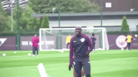 A Man In A Nike Shirt Is Standing On A Soccer Field GIF
