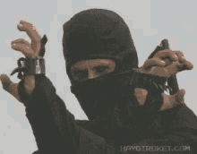 a man in a ninja mask is holding a gun in his hand