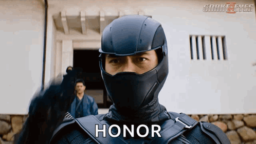 A Man In A Ninja Suit Says Honor In Front Of A Building GIF