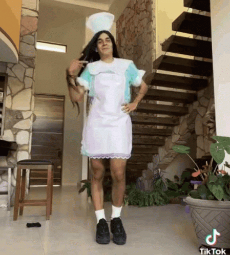 A Man In A Nurse Costume Is Standing In Front Of Stairs GIF