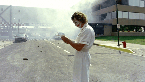 A Man In A Nurse 'S Uniform Is Standing In Front Of An Emergency Entrance GIF