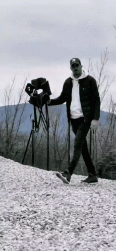 A Man In A Ny Hat Is Walking On A Pile Of Gravel . GIF