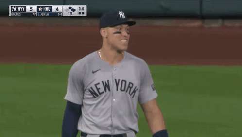 A Man In A Ny Yankees Jersey Holds His Fist Up GIF