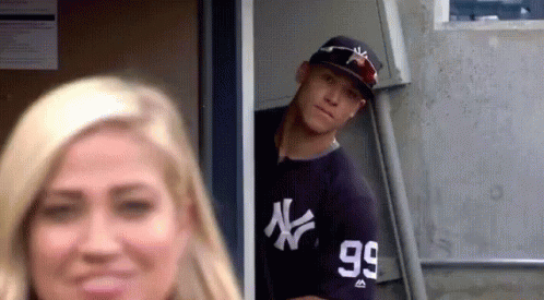 A Man In A Ny Yankees Jersey Is Peeking Out Of A Doorway . GIF