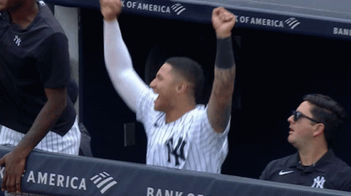 A Man In A Ny Yankees Uniform Holds His Fist Up In The Air GIF