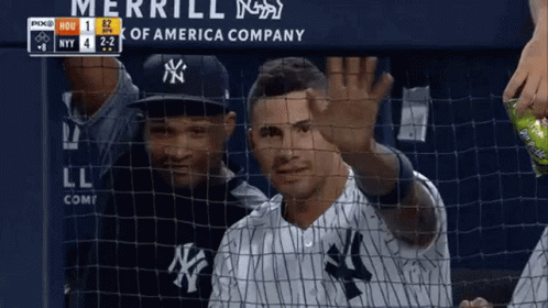 A Man In A Ny Yankees Uniform Is Waving Behind A Net GIF